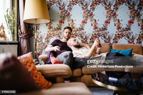 gay couple relaxing while watching tv - photo call stock-fotos und bilder