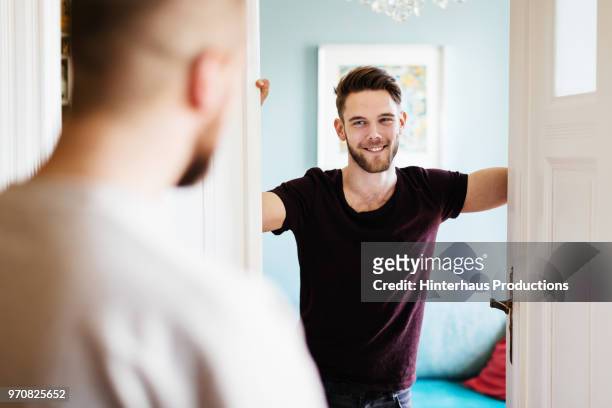 man opening door to greet his partner - door greeting stock pictures, royalty-free photos & images
