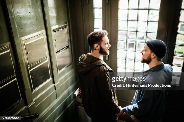 gay couple smiling while leaving house together - hinterhaus stockfoto's en -beelden