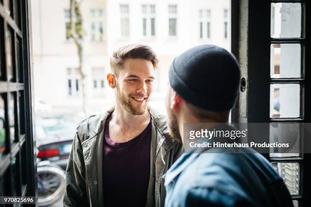 gay couple greeting each other - hinterhaus stockfoto's en -beelden