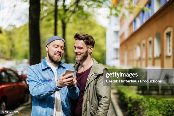 gay couple looking at map on smartphone together. - man talking at the phone outdoor stock-fotos und bilder