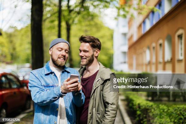 gay couple looking at map on smartphone together. - öppna och stäng knapp bildbanksfoton och bilder