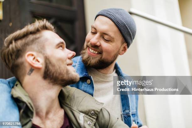 gay couple affectionately looking at one another - öppna och stäng knapp bildbanksfoton och bilder