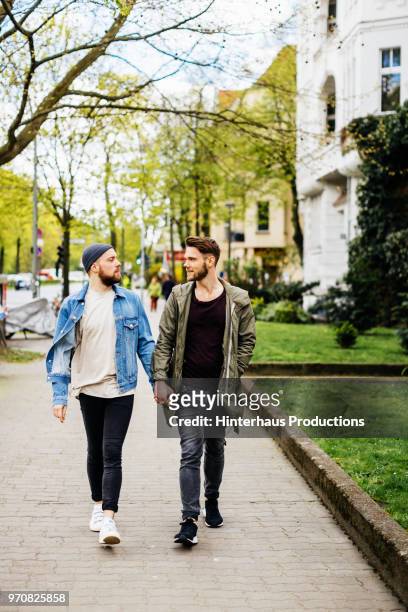 gay couple walking down street together - pulsante di apertura o di chiusura foto e immagini stock