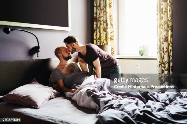 man kissing his partner before leaving for work - romantic young couple sleeping in bed stock pictures, royalty-free photos & images