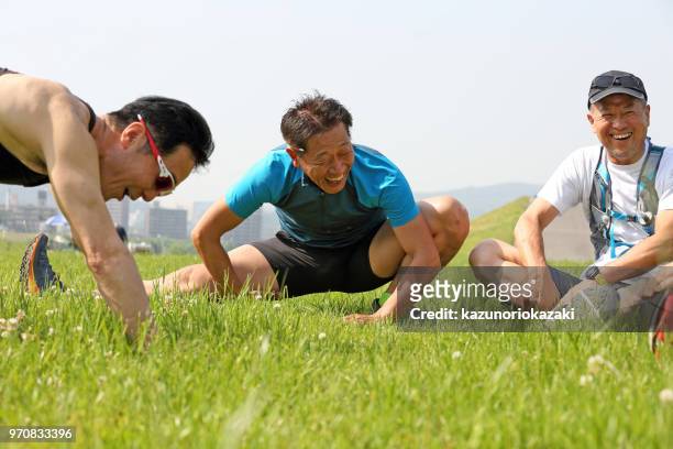 mann stretching auf gras - kazunoriokazaki stock-fotos und bilder