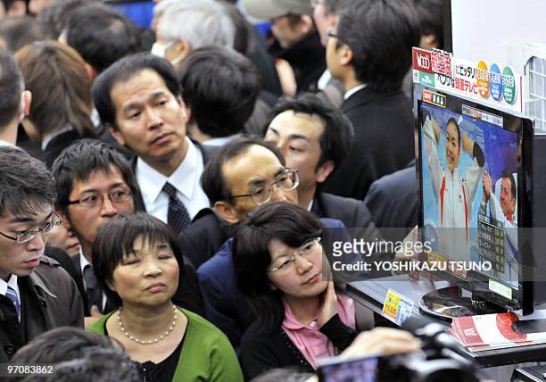 Japanese people watch South Korean figure skater Kim Yu-Na following her routine on a television screen at a Tokyo electrics shop on February 26,...