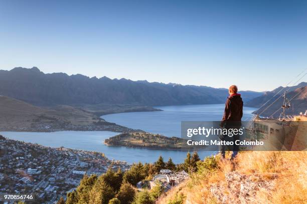 hiker looking at queenstown from lookout at sunrise, new zealand - queenstown ストックフォトと画像