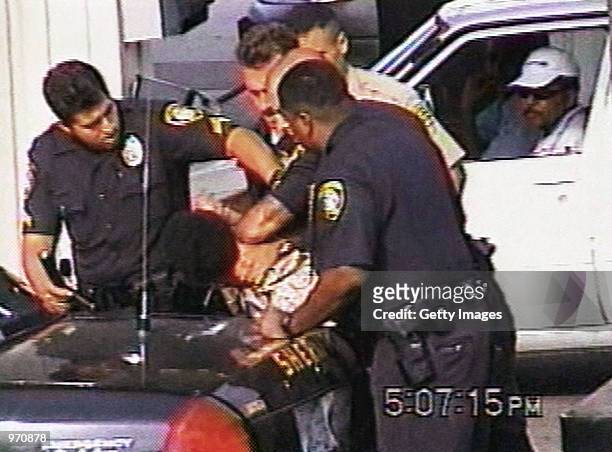 An unidentified man looks on as Inglewood police officers arrest 16-year-old Donovan Jackson on July 8, 2002 in Inglewood, California. Jackson was...