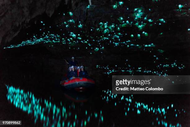 tourists looking at famous glowworm cave, waitomo caves, new zealand - cave stock pictures, royalty-free photos & images