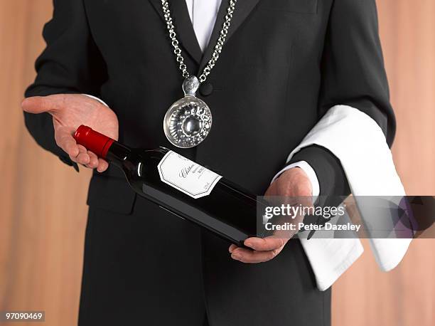 wine waiter sommelier presenting bottle of wine - sommelier stockfoto's en -beelden