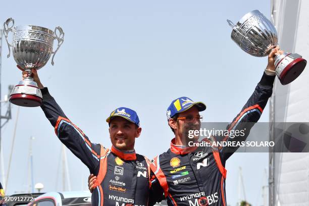 Belgium's driver Thierry Neuville and compatriot co-driver Nicolas Gilsoul of Hyundai i20 Coupe WRC, hold their trophies as they celebrate on the...