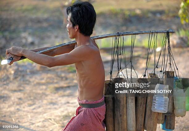 Cambodian man carries palm juice containers at Baphnom district in Prey Veng province, 80 kilometers east of Phnom Penh on February 24, 2010....