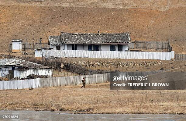 Nortk Korean female soldier walks across a dry landscape on the the banks of the Yalu River over 60 km northeast of Dandong, in China's northeast...
