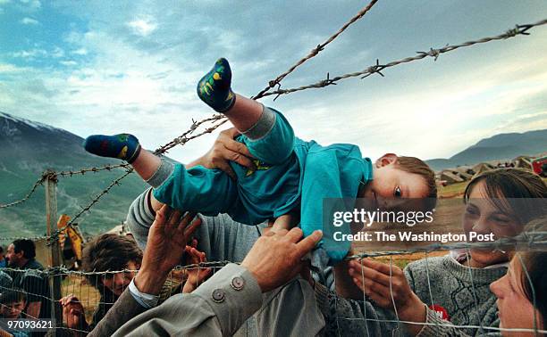 Feature Photography Pulitzer Prize. May 3, 1999. Kosovar refugee Agim Shala, 2 years old, is passed through the barbed wire fence into the hands of...