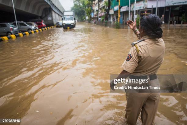 Rajni Jabre, a lady police officer, guides vehicles in a waterlogged street at Hindamata, Parel, on June 9, 2018 in Mumbai, India. Mumbai received...