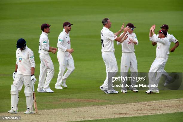 Rikki Clarke of Surrey celebrates with his teammates after dismissing James Vince of Hampshire as he walks off during the Specsavers County...