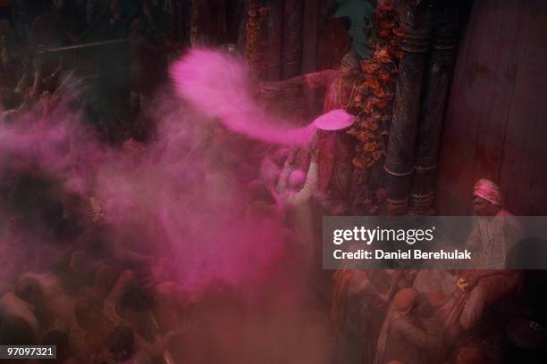 Hindu priest tosses dyed colour powder known as Gulal powder, passing the blessings of Lord Krishna to Hindu devotees as they play with colour during...