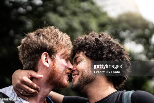 affection moment of gay couple in gay pride parade - gay kiss stock pictures, royalty-free photos & images