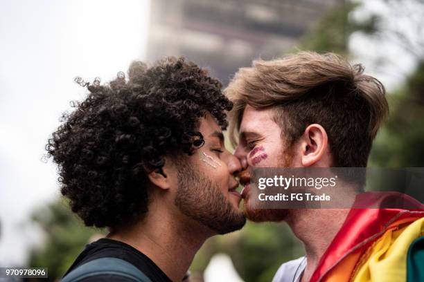tillgivenhet ögonblick av gay par i gay pride-paraden - gay man bildbanksfoton och bilder