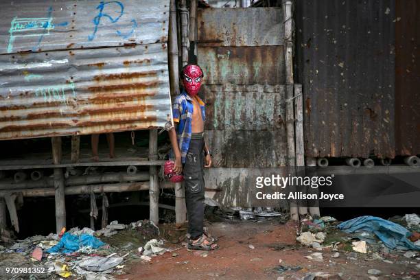 Child in a mask stands next to a polluted canal that leads to the Buriganga river in Shyampur June 10, 2018 in Dhaka, Bangladesh. Bangladesh has been...