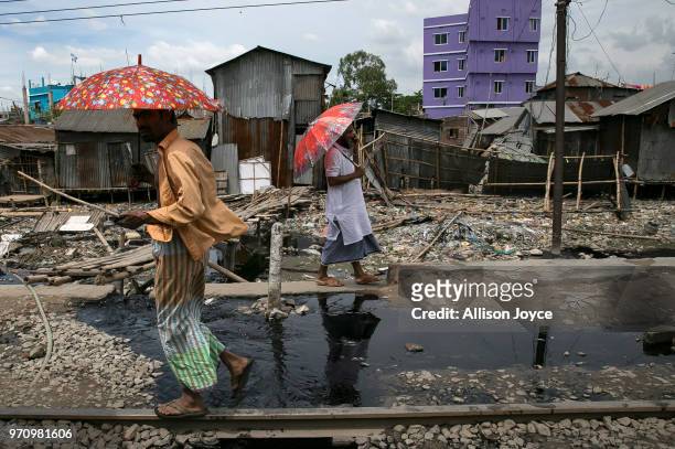 Men walk over dye and polluted water that is being released into a canal that leads to the Buriganga river in Shyampur June 10, 2018 in Dhaka,...