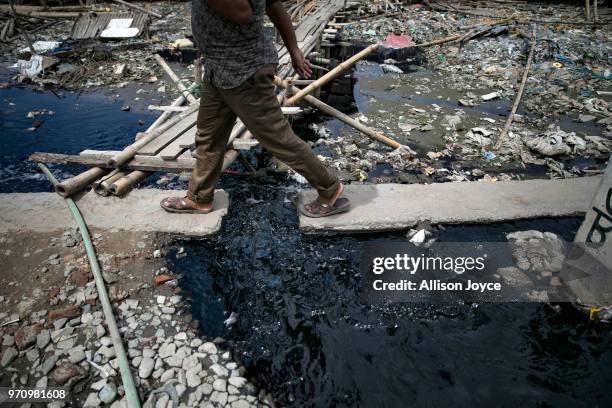 Man walks over dye and polluted water that is being released into a canal that leads to the Buriganga river in Shyampur June 10, 2018 in Dhaka,...