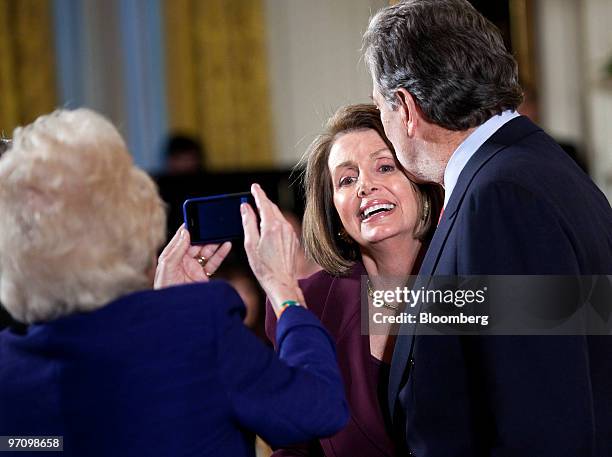 Woman photographs Speaker of the House Nancy Pelosi, center, and her husband Paul Pelosi before an awards ceremony in the East Room of the White...