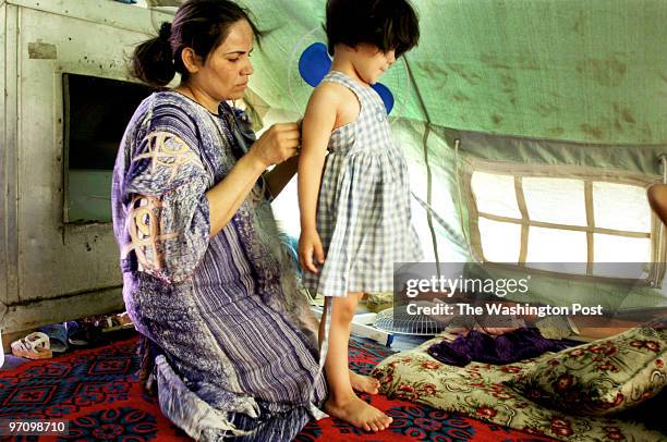 Fedwa Abdul Ghani dresses her daughter Najat Hassan in their tent in the Palestinian refugee camp in Baghdad. Palestinians who were once under the...
