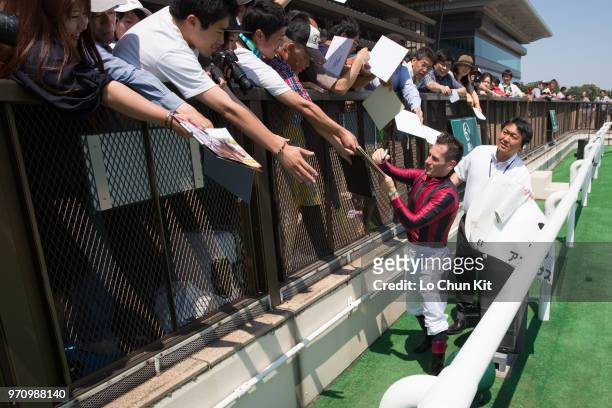 Jockey Mirco Demuro gives his autograph to Japanese racing fans after Akanesasu winning the Race 6 at Tokyo Racecourse on June 3, 2018 in Tokyo,...