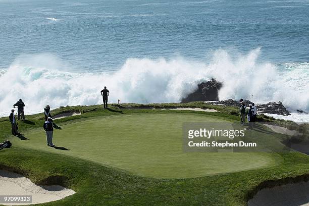 Surf crashes as a group plays the seventh hole during the final round of the AT&T Pebble Beach National Pro-Am at Pebble Beach Golf Links on February...