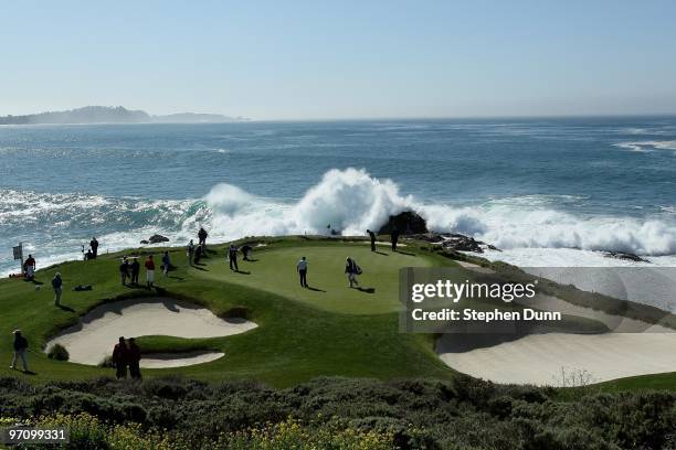 Surf crashes as a group plays the seventh hole during the final round of the AT&T Pebble Beach National Pro-Am at Pebble Beach Golf Links on February...