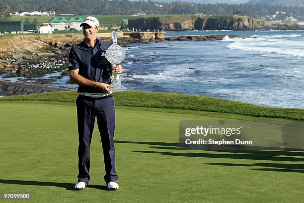 Dustin Johnson poses with the trophy on the 18th green after the final round of the AT&T Pebble Beach National Pro-Am at Pebble Beach Golf Links on...