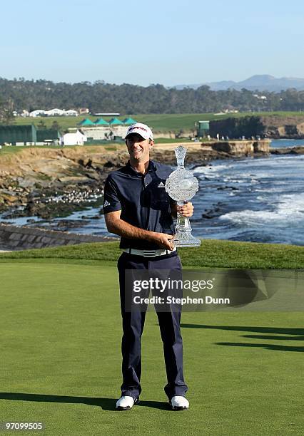 Dustin Johnson poses with the trophy on the 18th green after the final round of the AT&T Pebble Beach National Pro-Am at Pebble Beach Golf Links on...