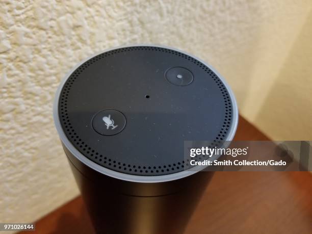Close-up of the top of an Amazon Echo smart speaker, using the Alexa service, on a light wooden surface in a suburban home setting, San Ramon,...