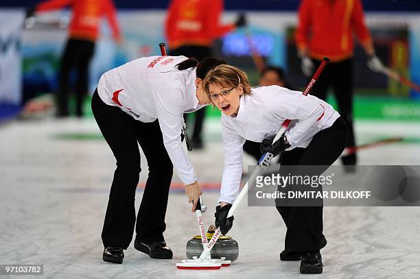Switzerland's Carmen Kueng and Janine Greiner sweep the ice during the bronze medal match against China in the Vancouver Winter Olympics women's...
