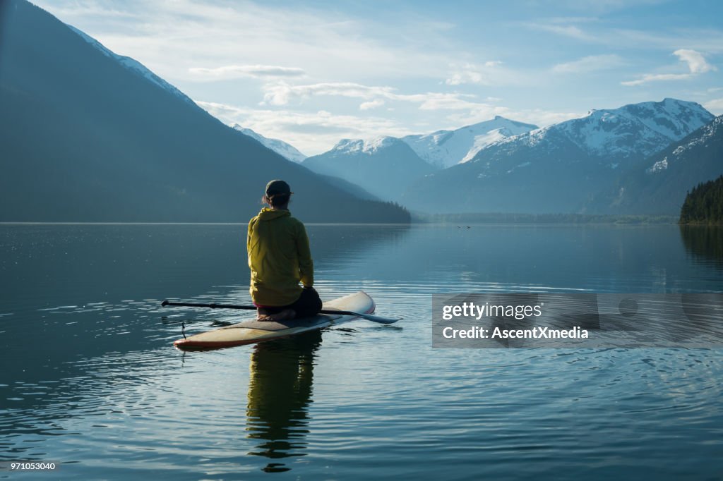 Femme lève-palette d’embarquer sur un lac de montagne vierge