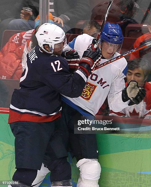 Ryan Malone of the United States checks Joni Pitkanen of Finland up the boards during the ice hockey men's semifinal game between the United States...