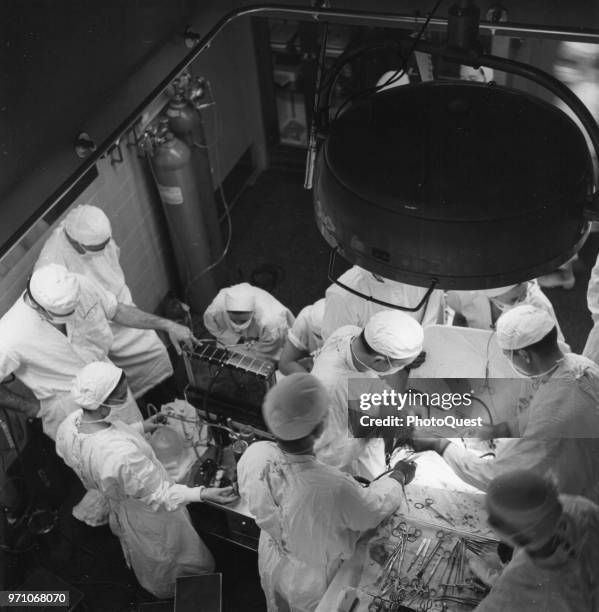 Overhead view of open heart surgery underway in an operating theater at Johns Hopkins University Hospital, Baltimore, Maryland, 1959. The chief...