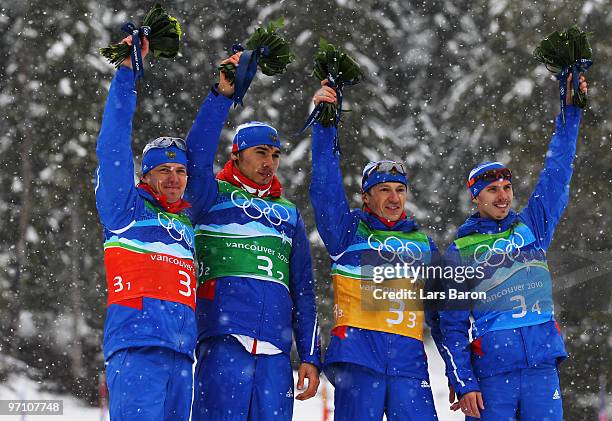 Ivan Tcherezov, Anton Shipulin, Maxim Tchoudov and Evgeny Ustyugov of Russia celebrate winning the bronze medal during the flower ceremony for the...