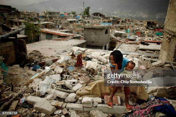 Sherider Anilus and her daughter, 9-month-old Monica, sit on the spot where her home collapsed during last month's 7.0 earthquake in the Fort...