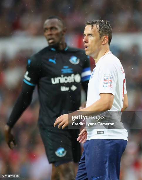 Phil Neville of England and Usain Bolt of the Rest of the World look on during the Soccer Aid for UNICEF 2018 match between England and the Rest of...