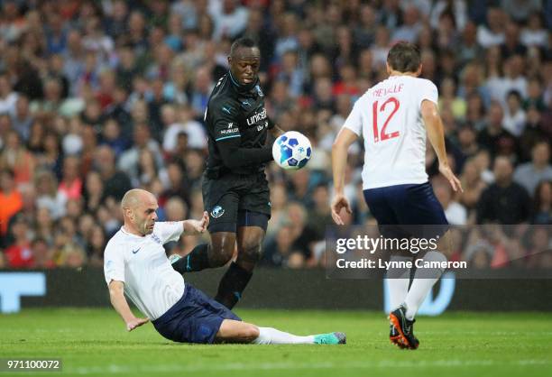 Usain Bolt of the Rest of the World takes on Danny Murphy of England and Phil Neville of England during the Soccer Aid for UNICEF 2018 match between...