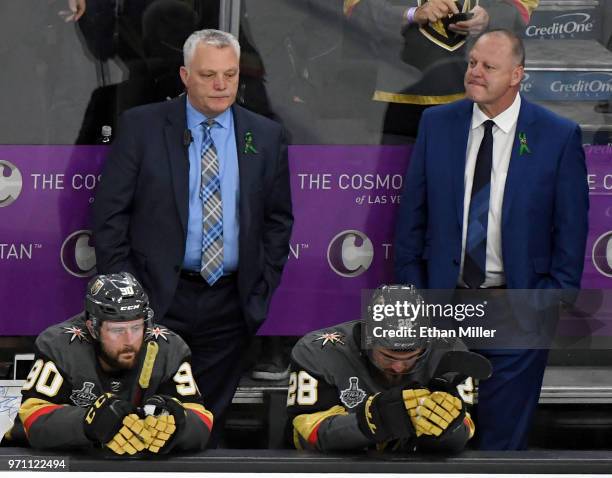 Tomas Tatar, assistant coach Mike Kelly, William Carrier and head coach Gerard Gallant of the Vegas Golden Knights wait at their bench as the...