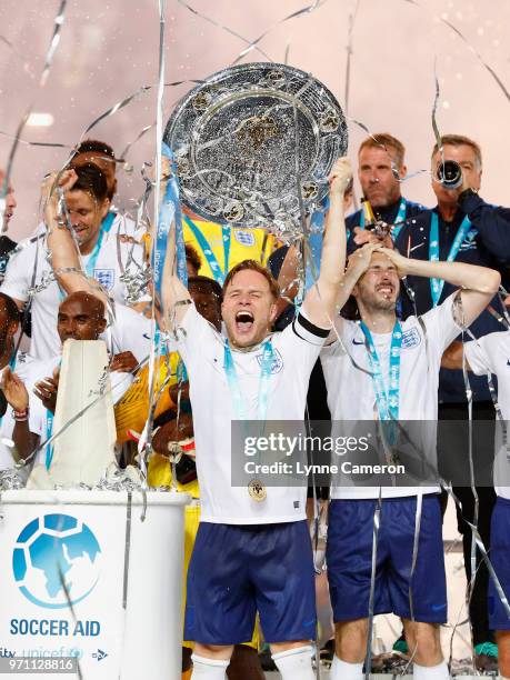 Olly Murs of England lifts the trophy in victory with team mates after the Soccer Aid for UNICEF 2018 match between Englannd and the Rest of the...