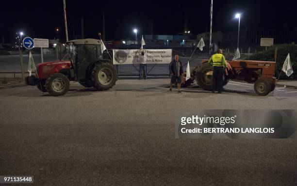French National federation of Agricultural Holders' Unions and Young Farmers union members install flags on a fence as they block the access of...