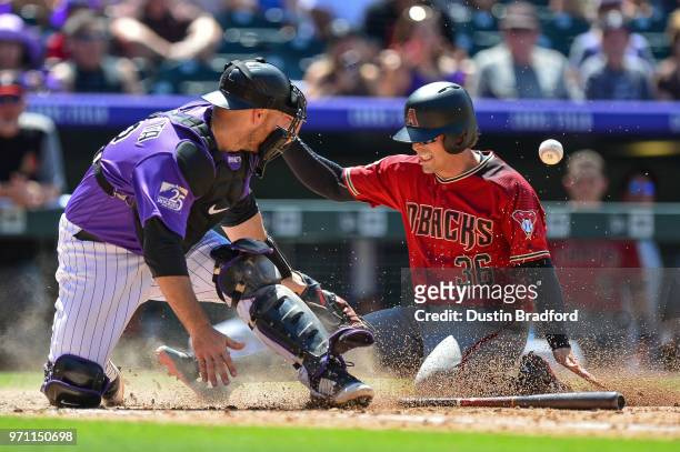 John Ryan Murphy of the Arizona Diamondbacks slides safely into home as Chris Iannetta of the Colorado Rockies attempts to apply a tag in the sixth...