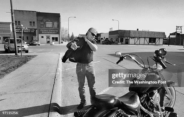Randy Weaver puts on his leather riding jacket before taking off to ride his Harley motorcycle. Photo taken in the Jefferson, Iowa town square which...