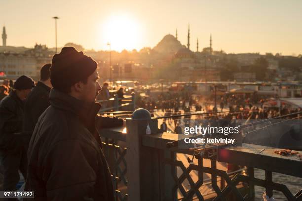 men fishing at sunset on the galata bridge, istanbul, turkey - kelvinjay stock pictures, royalty-free photos & images