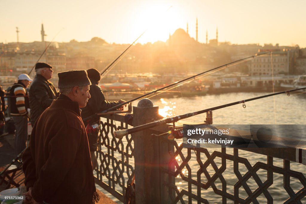 Männer Angeln bei Sonnenuntergang auf der Galata-Brücke, Istanbul, Türkei